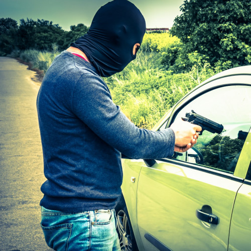 Male thief or terrorist is pointing a pistol on the driver, he trying to steal a car